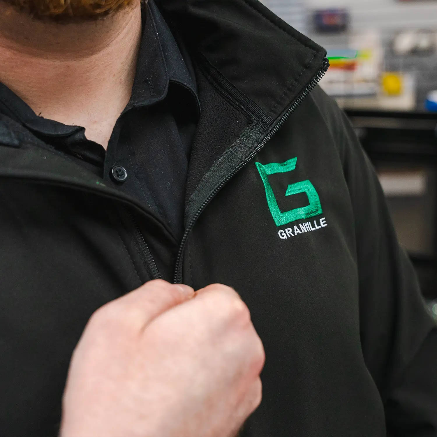 Close-up of a Granville Supplies employee zipping up a branded work jacket