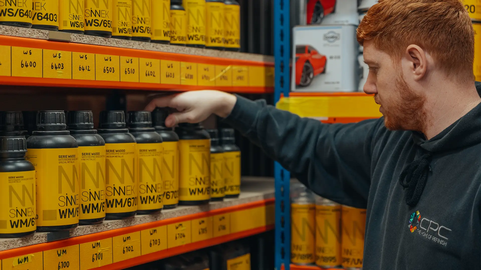 Car Paint Company warehouse employee selecting a Sinnek product from shelving