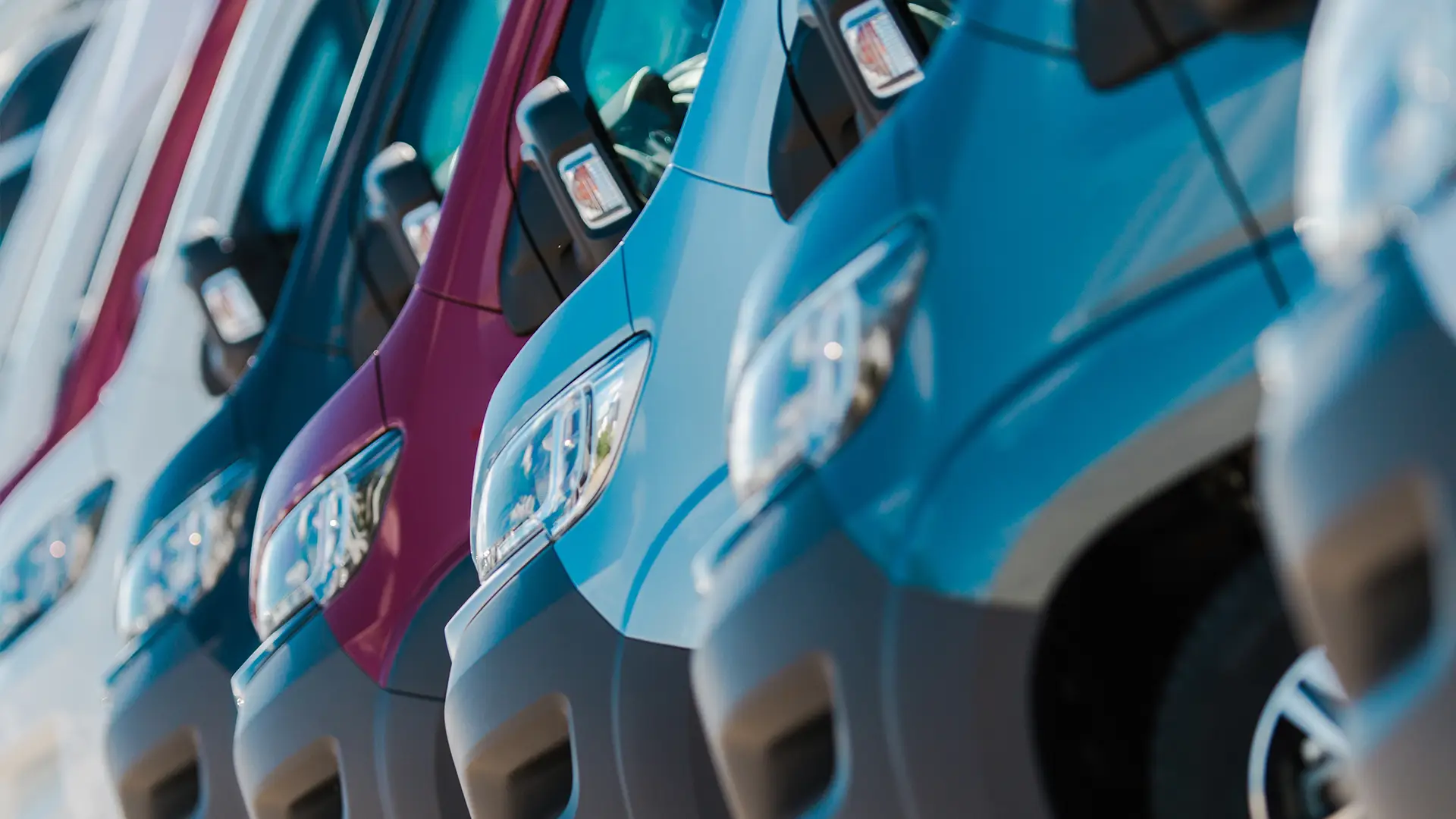 Side view of a fleet of white delivery vans parked in a row
